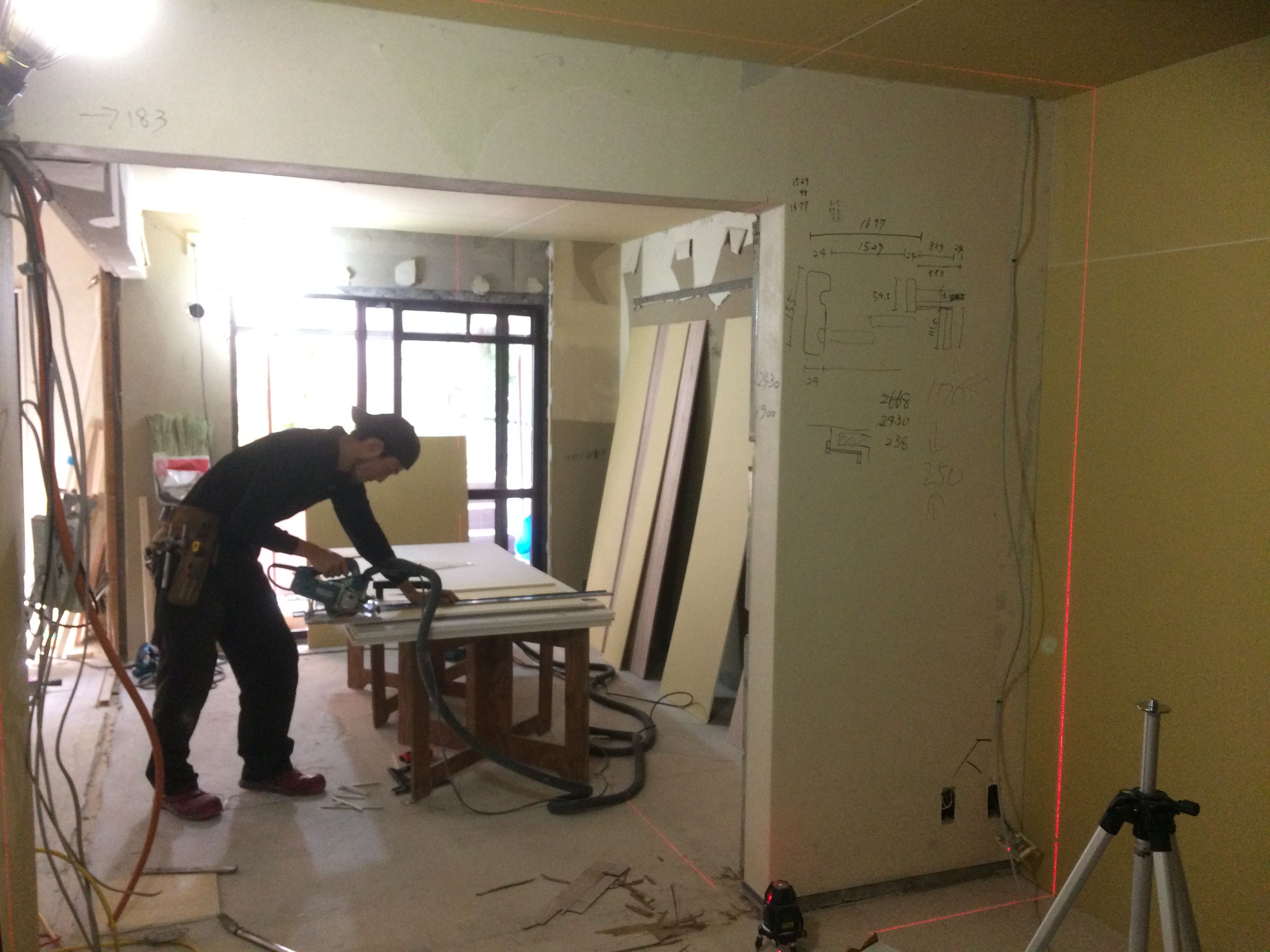 改修中の部屋で、丸ノコで材を切る大工
