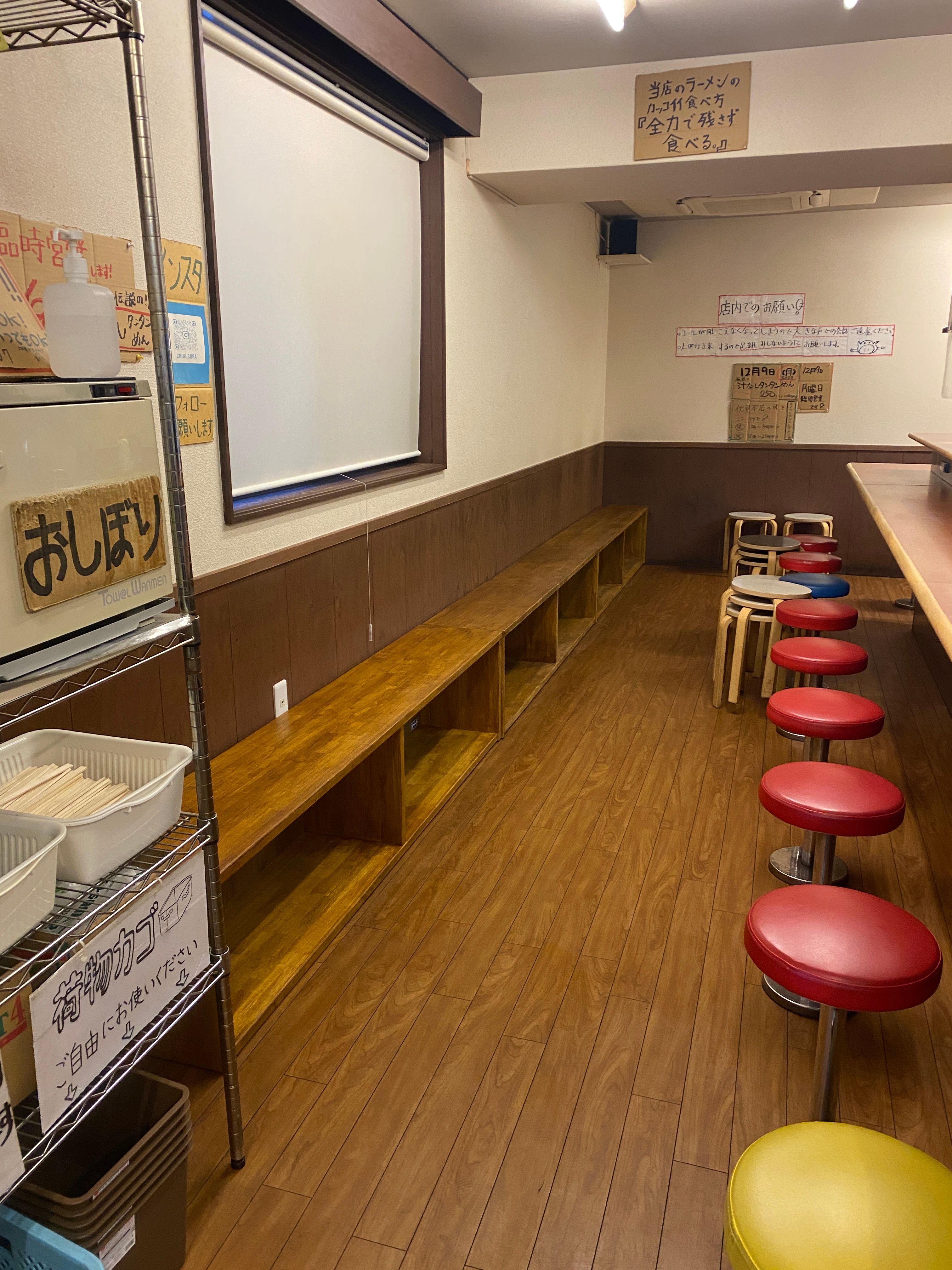ラーメン店の壁沿いにつくった木製の待合ベンチ